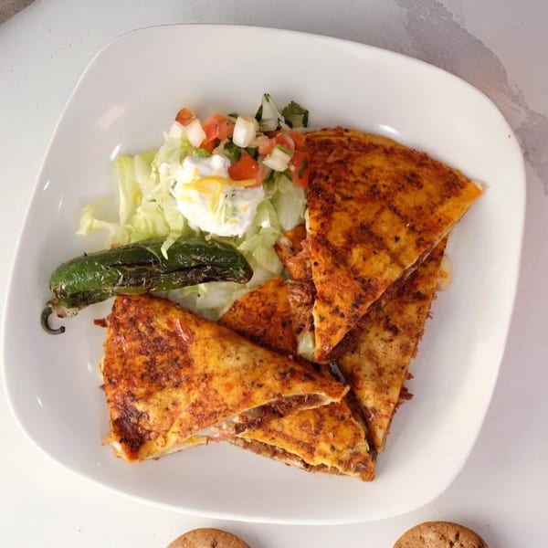 Halal Cuts quesadillas with a side of lettuce, pico de gallo, sour cream, and a grilled jalapeño.